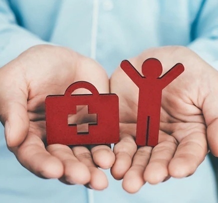 Imágen de manos con figuras de persona y de botiquin de primeros auxilios haciendo alusión a si el seguro de vida y seguro de salud son similares o diferentes